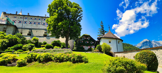 Burg Hohenwerfen in Austria is beautifully nestled in lush greenery, with the majestic Alps in the background. This medieval castle offers a picturesque view of history, nature, and architecture blend