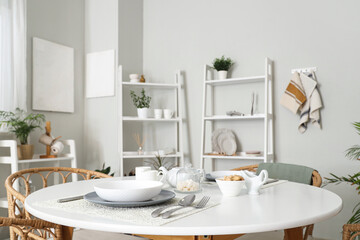 Served dining table and shelving units in interior of stylish kitchen