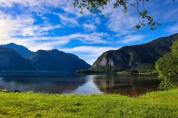 A serene lake near Hallstatt, Austria, reflecting the surrounding mountains and lush greenery, with clear skies and calm waters creating a picturesque scene. Perfect for nature lovers and outdoor enth