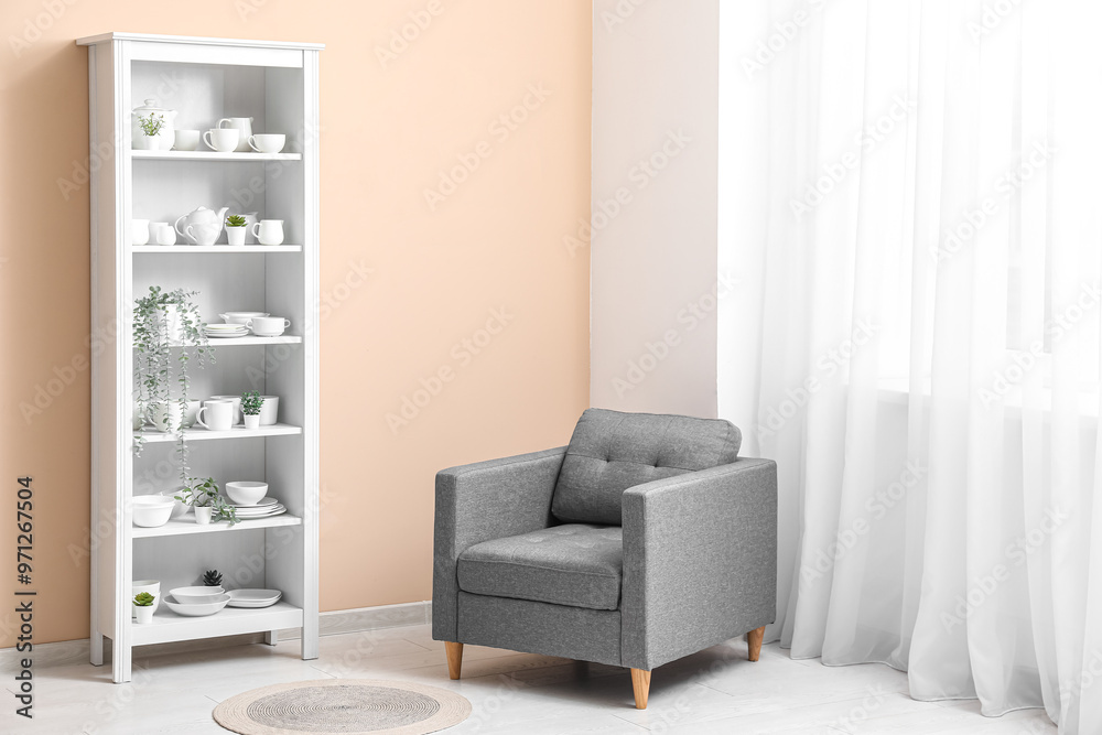 Wall mural Modern shelving unit with dishes and armchair near beige wall in room