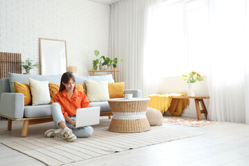 Pretty young woman using laptop at home