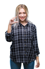 Young blonde woman over isolated background smiling and confident gesturing with hand doing size sign with fingers while looking and the camera. Measure concept.