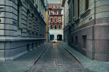 Venture into the heart of Riga's Old Town with this captivating image of a narrow, cobblestone street.