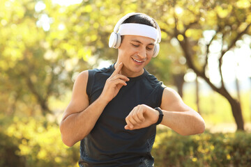 Sporty young man checking pulse after training outdoors