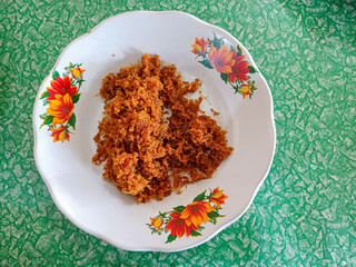 Padang Fried Chicken Spice Blend, crispy deep-fried seasoning typically used for fried chicken, served on a white plate with an orange floral pattern, placed against a green rocky background
