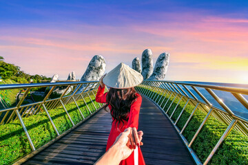 Women tourist holding man's hand and leading him to Golden bridge in Da nang, Vietnam.