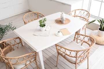 Houseplant, vases and notebook on table in dining room