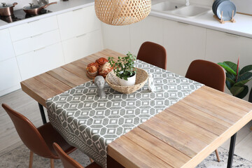 Statuettes, houseplant and wicker bowl on table in dining room