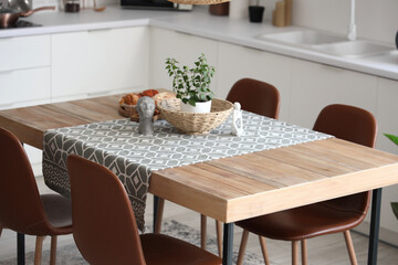 Statuettes, houseplant and wicker bowl on table in dining room