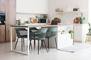 Interior of dining room with table, chairs and counters near white wall