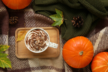 Autumn composition with cup of cocoa, pumpkins and wooden tray on plaid as background