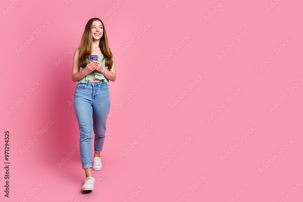 Wall mural full body portrait of pretty young girl walk phone look empty space wear top isolated on pink color 