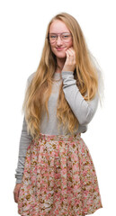 Blonde teenager woman wearing flowers skirt touching mouth with hand with painful expression because of toothache or dental illness on teeth. Dentist concept.