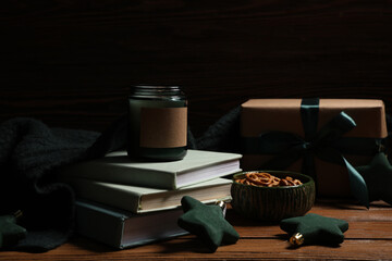 Beautiful composition with books, Christmas decor, gift box and bowl of pretzels on brown wooden background