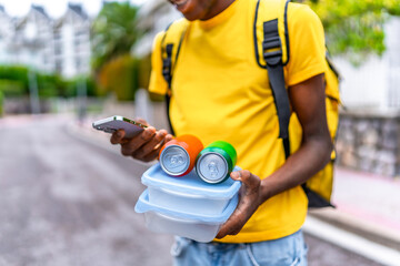 Delivery man using phone while holding food and sodas to deliver