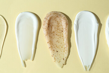 Fototapeta premium Smears of different cosmetic products on beige background, flat lay