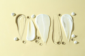 Smears of different cosmetic products on beige background, flat lay