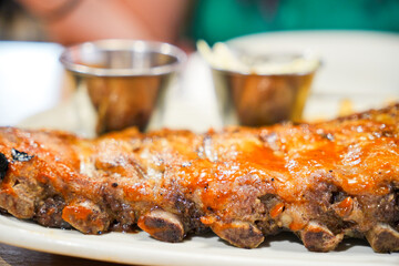A rack of ribs is served on a white plate with a side of mashed potatoes