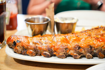 A large rack of ribs is served on a white plate with a side of fries