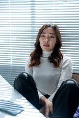 Young asian businesswoman sitting at desk looking concerned