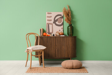 Burning candles in shape of pumpkins and forest bumps on commode near green wall at home