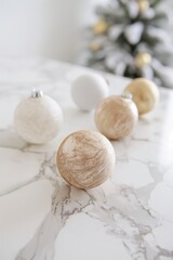 Christmas decorations in different colors placed on marble surface, blurred tree in background