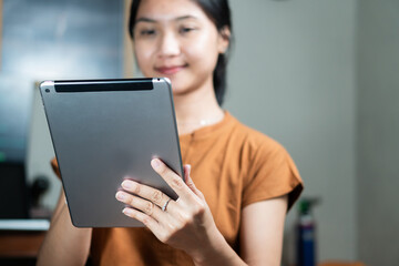 Fototapeta premium Young Woman Using Tablet in Cozy Indoor Setting