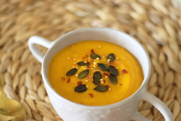 Pumpkin and potato creamy soup, bowl of grapes, jars of nuts and autumn leaves on the table. Selective focus.