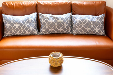 cozy interior of living room space with pillow on brown sofa, table