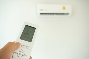Hand with remote control directed on the conditioner at room