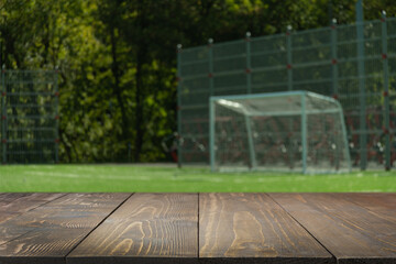 Empty wood table top with blurred outdoor football or soccer field. Abstract background. Mock up...