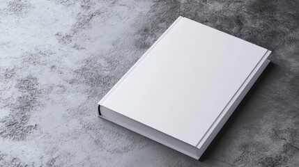 A white book is laying on a grey surface