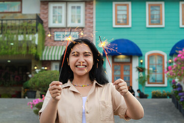 happy young asian woman holding sparkler celebrating new year eve in vintage house yard, outdoor garden