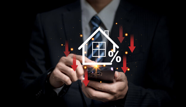 Businessman use smartphone with virtual home icon and down arrow for economical real estate and lower mortgage interest rates. Reduced prices for rental housing, Demand for home purchases decreases..