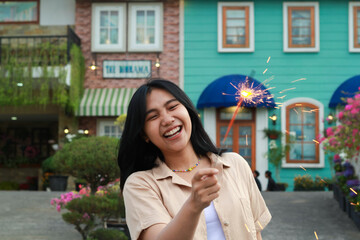 portrait of beautiful happy young asian woman holding sparklers fireworks to celebrate new year eve with garden party standing in outdoor vintage house yard