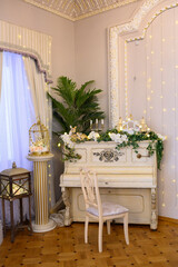 Antique white piano with flowers and sculptures in the interior of a 19th century mansion