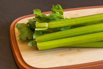Bunch of Celery on Wooden Board Close-Up on Dark Background