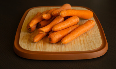 Bunch of Fresh Organic Carrots on a Wooden Chopping Board Close-Up