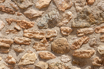 A beautiful texture of an old wall from gray and orange stones with cracks