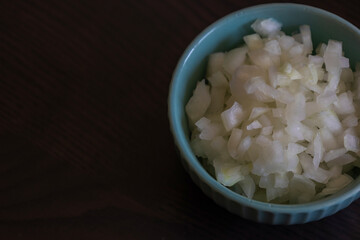 Chopped Onion in a Small Blue Bowl Close-Up on Dark Background