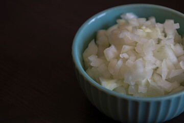 Chopped Onion in a Small Blue Bowl Close-Up on Dark Background