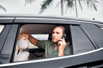 Man talking on a smartphone in a car by the palm trees
