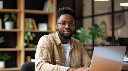Obraz premium portrait of a male tech support worker sitting in modern office working on laptop