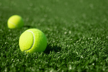 Yellow tennis ball on green sports ground with artificial grass covering. Close up. Copy space. Healthy lifestyle concept.