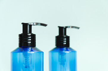 Fototapeta premium two plastic translucent blue bottles isolated on light blue background. template, cosmetic dispenser