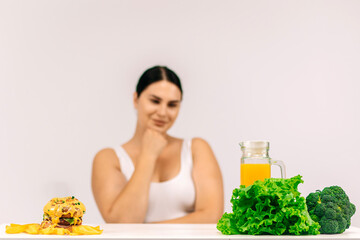 Full-figured woman on a light background choosing healthy food over less nutritious options. Perfect for promoting conscious decisions for a healthier and balanced diet