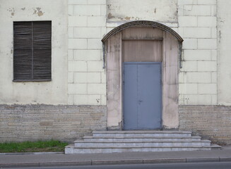 Closed grey metal door with a canopy and steps