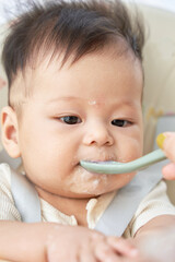 a baby sitting in a high chair with a spoon in his mouth