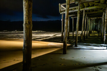 Ocean City, Maryland USA  A view of the beach and surf under the Ocean City pier at night.
