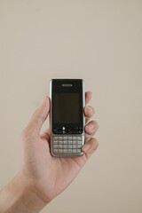 A hand holding a candybar phone on isolated background